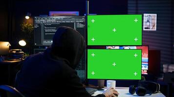 Dangerous man hacking using isolated screen PC, stealing credit card information and breaching banking systems. Hacker running code in apartment on chroma key computer display, close up, camera B photo