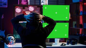 Cybercriminal using isolated screen PC in apartment hideout getting hacking attacks rejected by security. Hacker using chroma key computer monitor seeing access denied error message, camera A photo