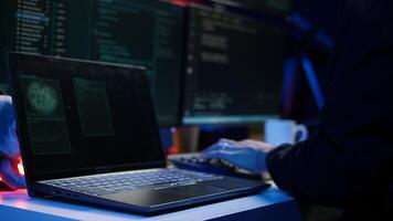 Hooded script kiddie taking laptop out of suitcase, prepared to launch DDoS attack. Close up shot of scammer at computer desk getting notebook from bag, starting work on malware script, camera B photo