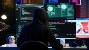 Malicious man hacking, stealing credit card numbers and manipulating banking systems for own personal gain. Evil hacker running code in apartment on computer monitor, camera A photo