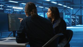 Team of engineers working together supervising server rows in computer network security data center. Multiethnic colleagues overseeing supercomputers providing memory resources for workloads photo