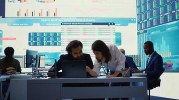 Business associate presents daily tasks order to enterprise administrator, discussing about funding and resources allocation in order to expand globally. Company analysts collaborate. Camera B. photo