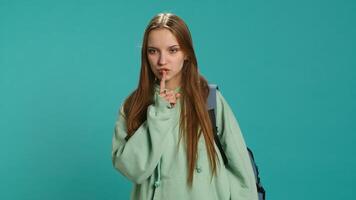 Stern woman doing shushing hand gesturing, irritated by noise, having negative mood. Girl placing finger on lips, doing quiet sign gesture, isolated over studio background, camera A photo