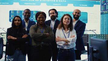Diverse group of business professionals posing together in monitoring room, multinational company headquarters. Executive management team working with big data screen in the office. Camera B. photo
