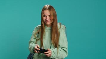 Young girl spamming controller buttons, disappointed after receiving game over screen. Woman upset after losing videogame, playing with gamepad, studio background, camera A photo