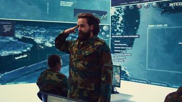 Sergeant presenting his salute with respect for the colonel and high ranking military officers, saluting the captains while he works on intelligence in command center, pride and duty. Camera B. photo