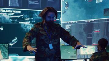 Command sergeant major employs high tech holograms to examine real time data for a mission, working on ways to protect the national coast line. Creating an attack plan. Camera A. photo