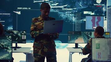 Infantry unit leader examines big data on a screen in military monitoring room and command center. Male army officer ensures national safety, strategic and tactical intelligence. Camera B. photo
