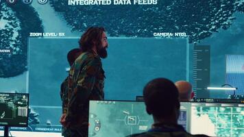 Military surveillance officers talking next to a big screen in general headquarters for cyber operations, control and monitoring to manage national security and army communications. Camera A. photo