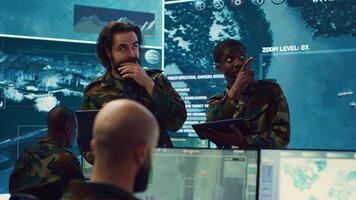 Diverse team of infantry unit leader and commander gather intelligence via radar surveillance, examine a world map to ensure national safety. Officers operating in mission control center. Camera A. photo