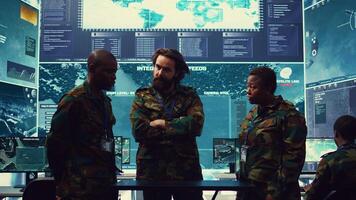 Diverse army officers examining real time data on a hologram, working with high tech holograph in a military command center for surveillance. Gather intelligence to support field troops. Camera B. photo