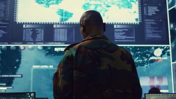 General of the army overseeing special reconnaissance mission in control center, undertake intelligence gathering operations with CCTV footage and a world map on a big screen. Camera B. photo