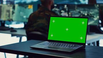 Laptop showing isolated mockup screen in army base of operations, military personnel working on gathering crucial information for a new mission. General headquarters with high tech. Camera A. photo