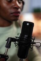 Closeup of social media content creator talking into vlogging microphone with subscribers answering question while recording entertainment podcast. Woman vlogger hosting on air talk photo