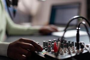 Closeup of influencer woman checking sound of professional mixer while recording online vlog talking with subscribers using microphone. Content creator filming for social media. On air talk show photo