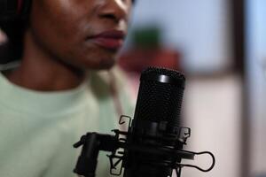 Closeup of african american vlogger woman talking into professional microphone with subscribers answering question while filming podcast. Social media content creator hosting on air talk photo