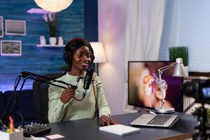 Content creator woman talking into production microphone answering subscribers questions while recording for social media in filming studio at home. Influencer hosting on air live show photo