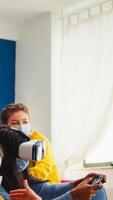 Black woman experiencing virtual reality headset playing games wearing face mask while friends having fun drinking beer. respecting distancing wearing face mask to prevent infection with virus, photo