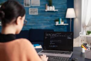 Student writing code on laptop in home office. Freelance programmer developing software. Freelancer coder working remote typing on keyboard. Software tester debugging looking for errors. photo