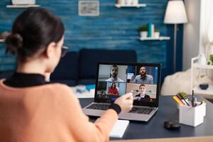 Woman in a briefing videocall with team on laptop. Freelancer working from home office having group online meeting on laptop. Student discussing with colleagues in webcam conference. photo