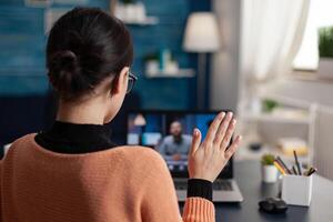 Student raising hand in online videocall class. Freelancer with laptop in home office introducing herself to a new client. Greeting gesture in conference interview with employer. photo