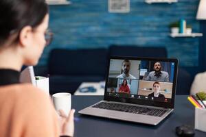 Freelancer having group online meeting on laptop. Colleague briefing videocall with team in home office. Student studying from home discussing with colleagues in webcam conference. photo