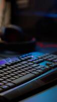 Close up of professional RGB keypad in empty gaming room prepared for streaming online tournament, display with first person shooter playing on it. Game studio with powerful computer photo