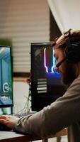 Cyber sport gamer wearing headphones playing first person shooter videogame participating in eSports tournament perforing at RGB prowerful personal computer. Pro cyber streaming gaming championship photo