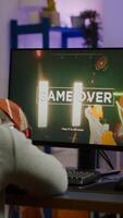 Game over for sad gamer playing shooter games on powerful computer using RGB keyboard in gaming room. Defeated man with headphones streaming online cyber performing through online tournament photo