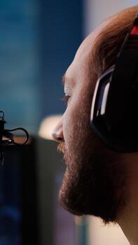Portrait of cyber talking on stream chat with players using micorphone and powerful computer. Streamer man sitting on gaming chair playing space shooter game during online esports tournament. photo