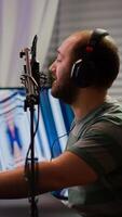 Professional digital player with headphones streaming game with modern graphics for shooter online game championship. Pro gamer checking sound at mixer playing online game in gaming studio photo