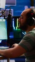 Competitive gamer with headphones using stream chat on powerful computer playing online shooter game late at night. Virtual online streaming cyber checking sound performing in gaming tournament photo