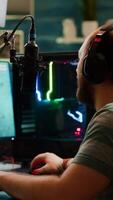 Over shoulder footage of professional streamer with headset playing digital space shooter games on RGB powerful computer using microphone and mouse. Videogamer man streaming online games photo