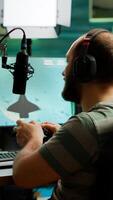 Man streamer playing space shooter games using professional RGB keyboard and wireless joystick. Pro gamer talking into microphone on streaming chat during online tournament photo