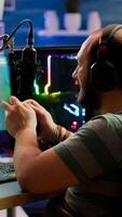 Concentrated gamer playing shooter game in gaming competition using wireless controller wearing professional headphones. Online streaming cyber performing during tournament using RGB powerful PC photo