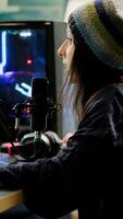 Cyber woman streamer looking at camera and smiling while streaming chat is open. Videogamer streamer playing space shooter game at gaming home studio equipped with professional equipment photo