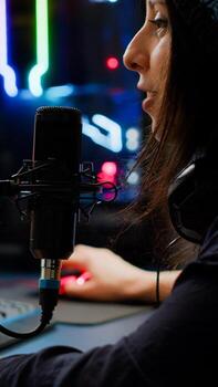 Close-up of streamer playing first person shooter game using RGB keyboard and mouse. Gamer talking on streaming chat with other players during esport tournament late at night in gaming studio photo