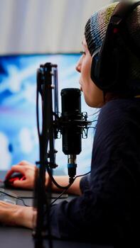 Pro cyber woman talking at streaming professional microphone in gaming home studio with open stream chat. Gamer performing in online tournament using powerful personal computer with RGB and headset photo