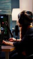 Woman streamer checking sound using professional mixer for streaming games in gaming home studio. Pro gamer playing first person shooter games talking with team mates on open chat photo