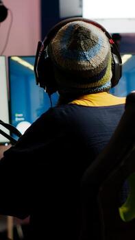 Back shot of pro gamer woman playing first person games using RGB keyboard in home studio. Gamer streaming gameplay using professional gaming powerful computer during online competition photo