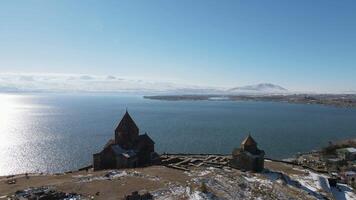 Aerial view of a high hill and a wooden temple on its top. Footage. Beautiful sea with rippling surface and blue cloudy sky. video