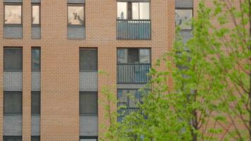 Panoramic view of facade of residential building. Stock footage. View of windows of modern apartment building on sunny day. Beautiful facade with windows of residential building in modern complex video