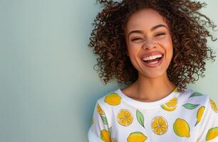 Woman With Curly Hair Smiles Against a Green Wall While Wearing a Lemon-Patterned Shirt photo