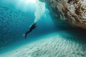 Underwater Scuba Diver Exploring a Coral Reef Cave With Schools of Fish photo