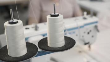 A closeup view of colorful thread spools and a sewing machine inside a tailor workshop video