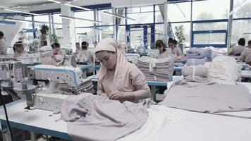 A group of textile factory workers is busy sewing and creating garments in an industrial setting video