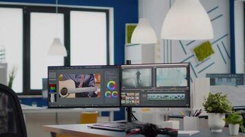 Empty modern creative agency office with dual monitors setup with processing film montage. editing start up studio company with no people in it and post production software on pc displays video