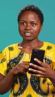 Vertical Friendly positive woman talks on online videocall with a smartphone, waving at webcam and chatting with friends in studio. Smiling cute girl having a casual discussion on videoconference. Camera A. video
