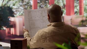 negocio propietario utilizando digital herramientas a revisión y evaluar oficina espacios planos, enfoque en arrendamiento un funcional y creativo espacio de trabajo búsquedas para real bienes, estrategia planificación. cámara una. video