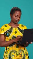 Vertical Young woman freelancer navigating on online webpages in studio, browsing information on device connected to internet. Charming traditional girl carries a portable pc. Camera B. video